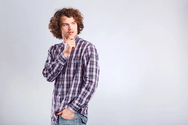 Een curly-haired man denkt met een ernstige emotie. — Stockfoto