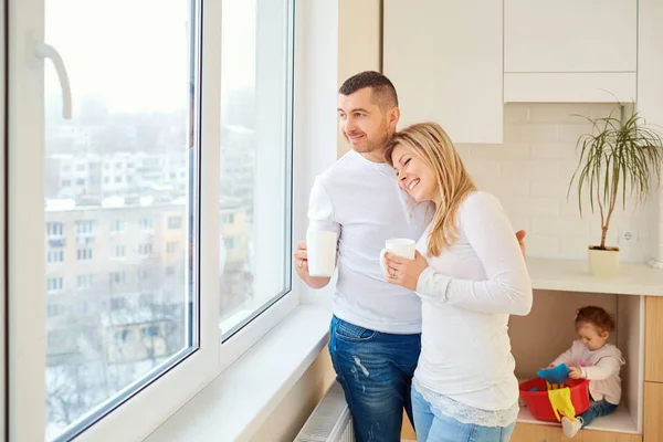 Happy parents hug together at the window. — Stock Photo, Image