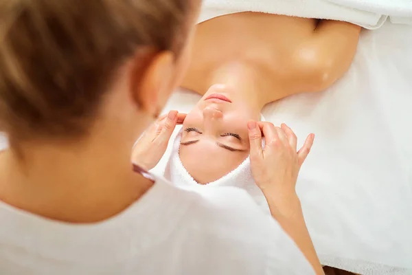 Hermosa mujer en un masaje facial en un salón de spa —  Fotos de Stock