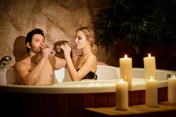 Casal descansando na banheira com velas no centro de spa . — Fotografia de Stock