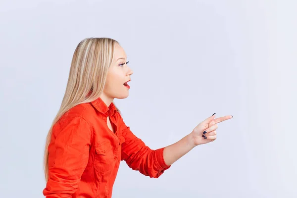 Young blond woman , with positive emotions points to a gray back — Stock Photo, Image