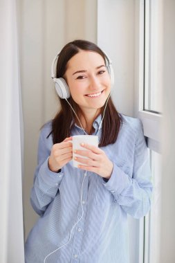 Genç bir kızla Kulaklığımda pencerenin kenarında elinde kupa