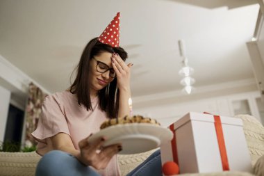 Bir pasta ile doğum gününde bir şapka giymiş bir mutsuz al kızdır