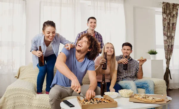 Eine Gruppe von Freunden isst Pizza, während sie auf der Couch sitzen. — Stockfoto