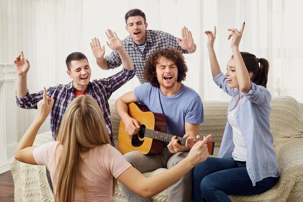 Un gruppo di amici con una chitarra cantare canzoni ad una festa al coperto — Foto Stock