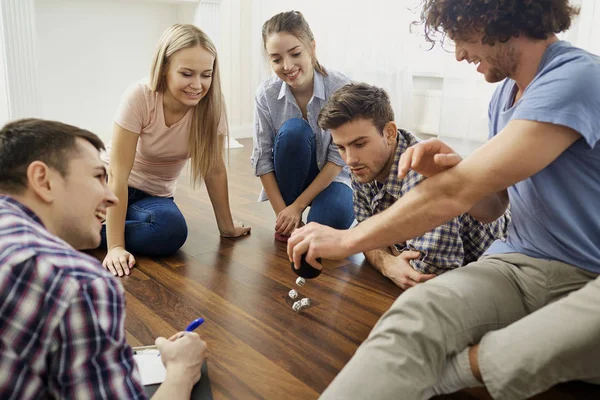 A group of friends play board games on the floor indoors. — Stock Photo, Image