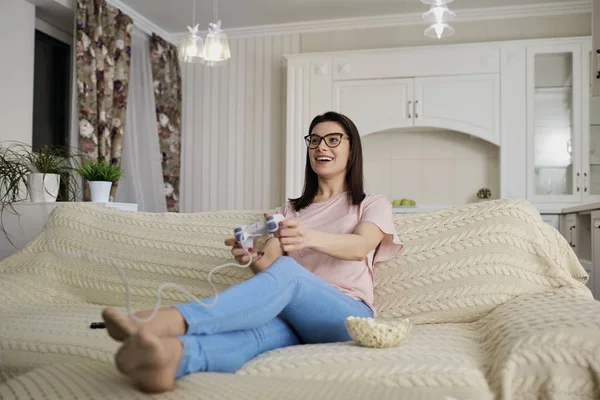 Lány barna szemüveg a pattogatott kukorica, s video játékok-ban játszik — Stock Fotó
