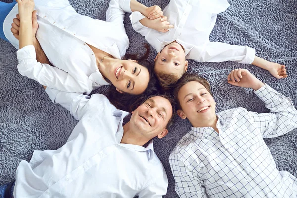 Yerde yatarken gülümseyerek mutlu bir aile. — Stok fotoğraf