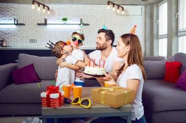 Bir pasta ile mutlu bir aile doğum günü partisi kutluyor.