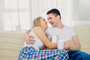 Bir adam ve bir kız pijama kanepe aga üzerinde oturan sarılıyorlar