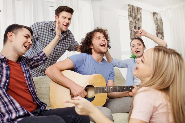 Группа друзей с гитарой поют песни на вечеринке в помещении — стоковое фото
