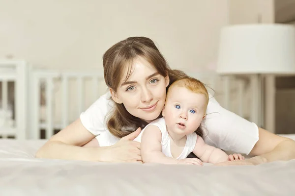 Retrato de una madre con un bebé acostado en la cama . — Foto de Stock