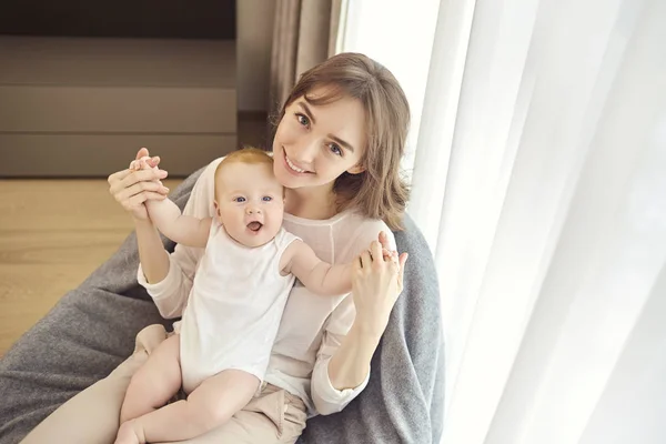 Önünde bir sandalyede oturan kucağında bir bebekle anne — Stok fotoğraf