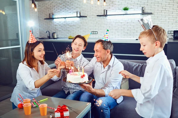 En familj med en ljus kaka firar en födelsedagsfest. — Stockfoto