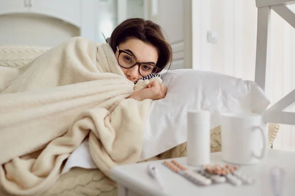 A chill woman under the blanket on the bed in the room. — Stock Photo, Image