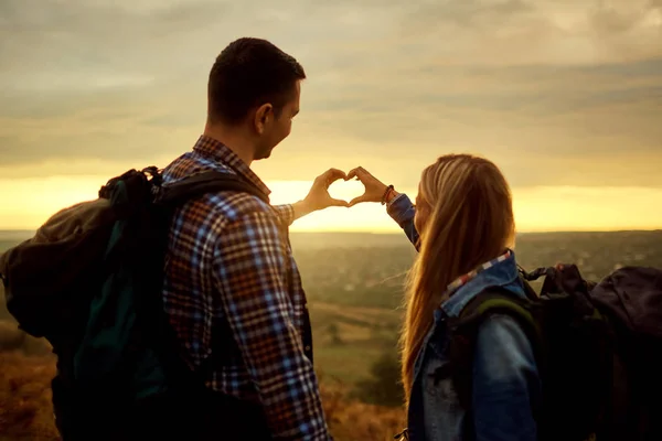 A couple of tourists with backpacks made a symbol of the heart w — Stock Photo, Image
