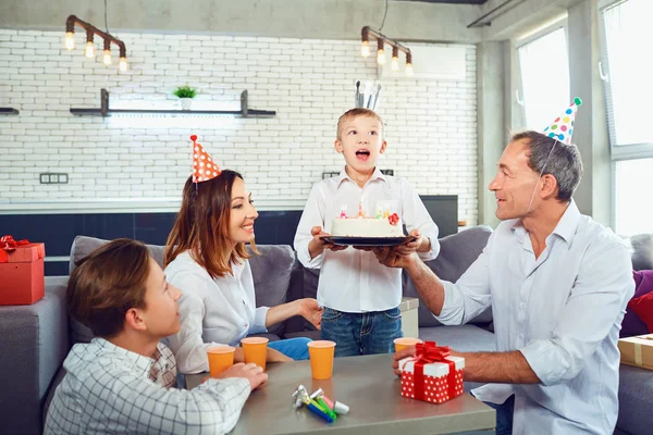 Una familia con un pastel de velas celebra una fiesta de cumpleaños . — Foto de Stock