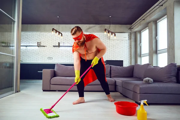 A fat, funny man in a superhero costume is cleaning the house.