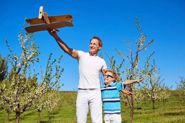 Baba ve oğul bir uçakla Bahar, yaz aylarında bahçede stand — Stok fotoğraf