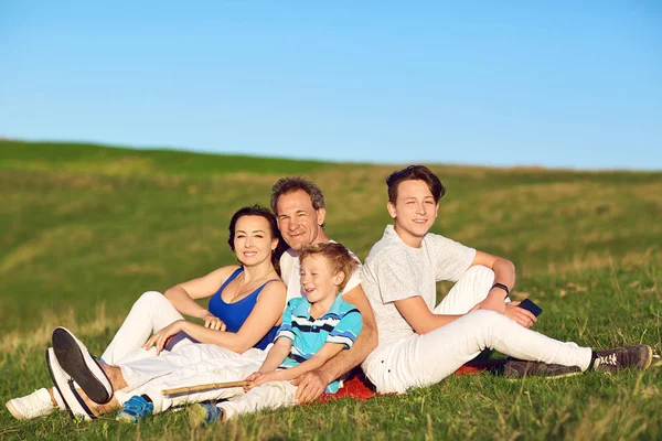 Famiglia felice seduta sulla natura in primavera, estate . — Foto Stock