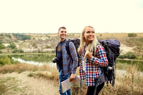 Um jovem casal de turistas com um mapa em uma caminhada na natureza — Fotografia de Stock