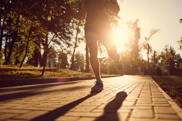 Mężczyzna runner jest uruchomiony w parku o zachodzie słońca. — Zdjęcie stockowe