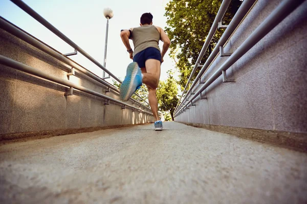 A male runner runs along the road to the park. — Stock Photo, Image