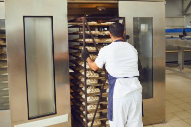 Fırıncı fırındaki fırından ekmek tepsisi itiyor..