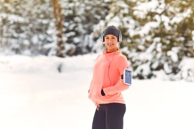 Kız sporcu kışın parkta dikilirken gülümsüyor