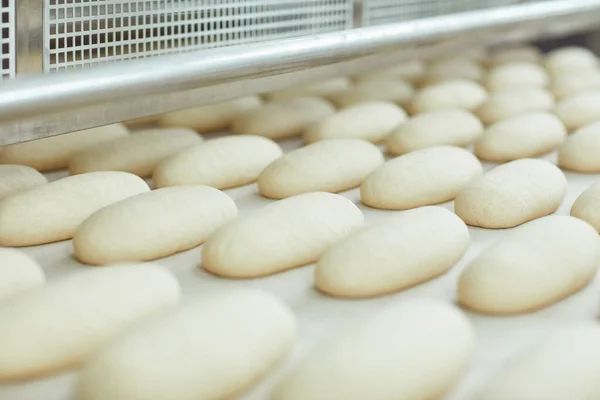 빵집의 자동 장비 라인에서 생 빵을 만들고 있습니다.. — 스톡 사진
