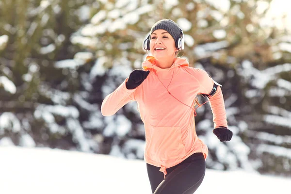 Kvinde jogging i sneen på naturen om vinteren - Stock-foto