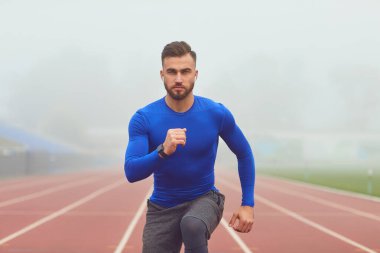 Sporcunun siste stadyumda çömeldiği adam.