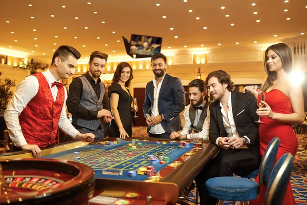 Grupo de personas felices hacen apuestas apostando en la mesa de ruleta en el casino . —  Fotos de Stock