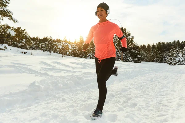 Woman runs in the forest at sunset in winter. — Stock Photo, Image