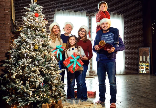 Family in Santas hats decorates the Christmas tree at home on Christmas. — Stock Photo, Image