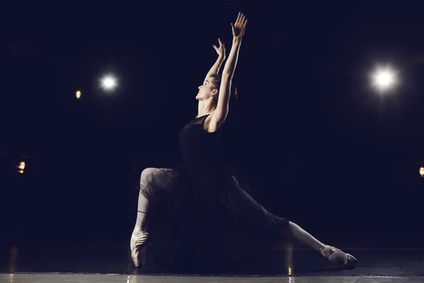 Woman ballet dancer on black background.