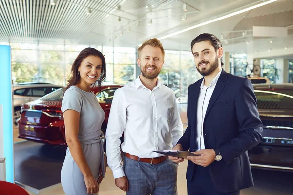 Pár si koupí nové auto. Muž a prodavač aut si potřesou rukou. — Stock fotografie