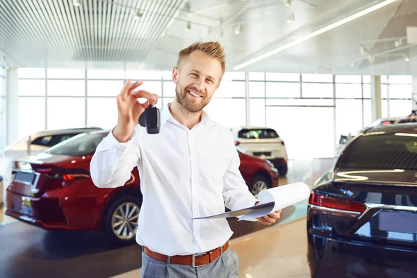 A car dealer holds keys in his hand in a showroom.