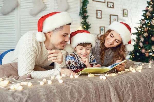 Família lendo um livro em uma casa com uma árvore de Natal. — Fotografia de Stock