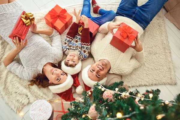 Happy family with Xmas gifts lying on floor — Stock Photo, Image