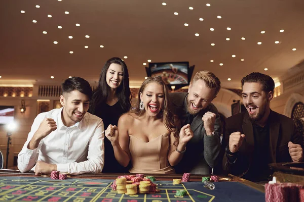 La gente feliz está apostando en el póquer de ruleta en un casino —  Fotos de Stock