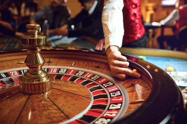 Hand of a croupier on a roulette whell in a casino. — Stock Photo, Image