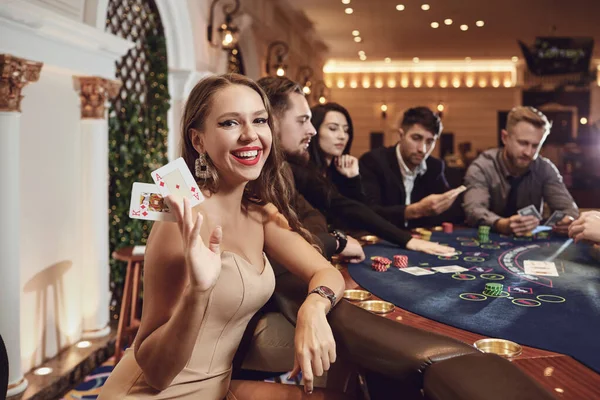 Meisje met kaarten in haar handen lacht speelt poker in een casino. — Stockfoto