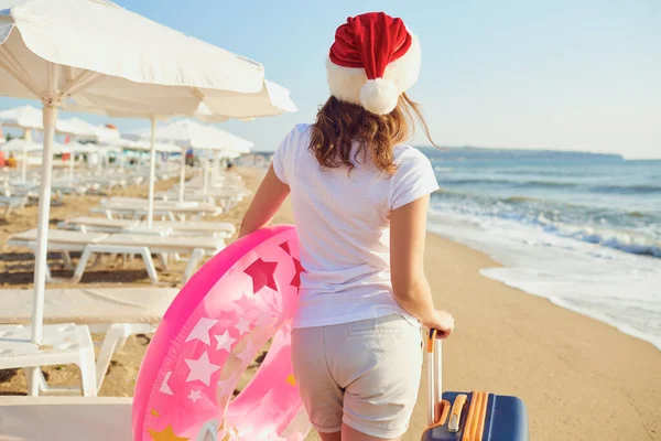 Дівчина в капелюсі Санта на березі моря . — стокове фото