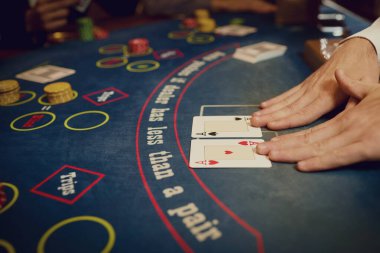 Kumarhanedeki bir masada krupiyenin elinde poker kartları var..