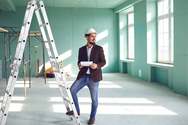 Homem barbudo Foreman em um capacete branco em um quarto em um canteiro de obras — Fotografia de Stock