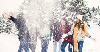 Friends throw fun snow in the park in winter
