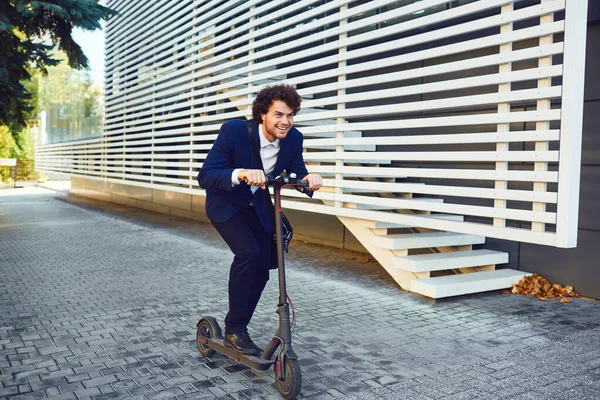 Молодой человек в шлеме ездит на электрическом скутере по городской улице летом — стоковое фото