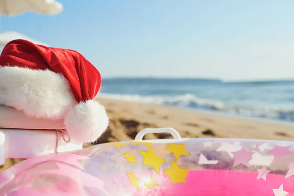 Santa Claus hat on the beach by the sea. — Stock Photo, Image