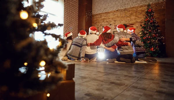 Achteraanzicht van volwassen mannen en vrouwen in Santa hoeden samen zittend hand in hand opgeheven — Stockfoto